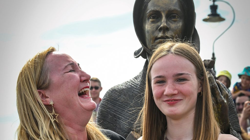 Evie Swire and her mother Anya Pearson stand in front of a statue of Mary Anning.