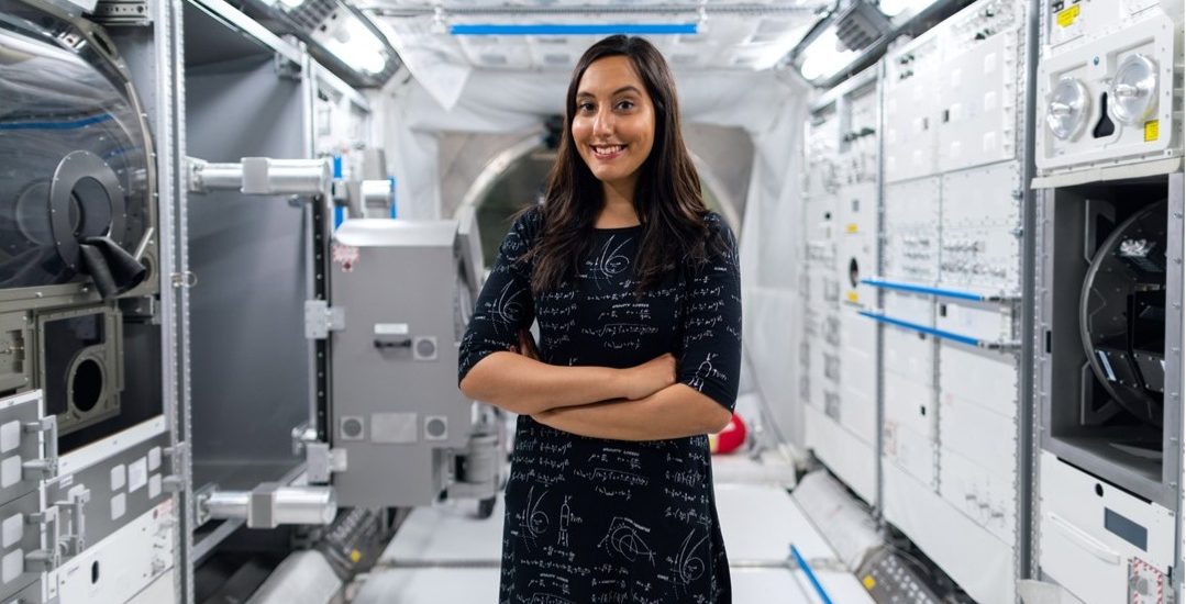 A woman stands in a futuristic tunnel full of instruments for use in space research.