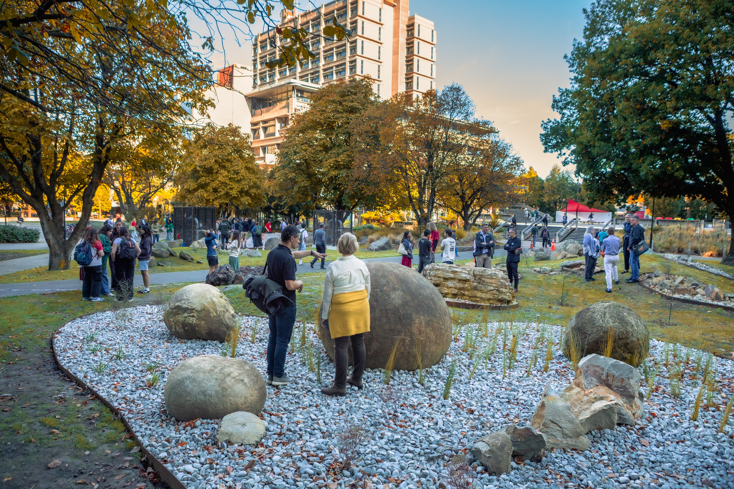 Visitors walk around an outdoor rock garden on the University of Canterbury campus in New Zealand, with boulders of different lithologies forming an interactive path.