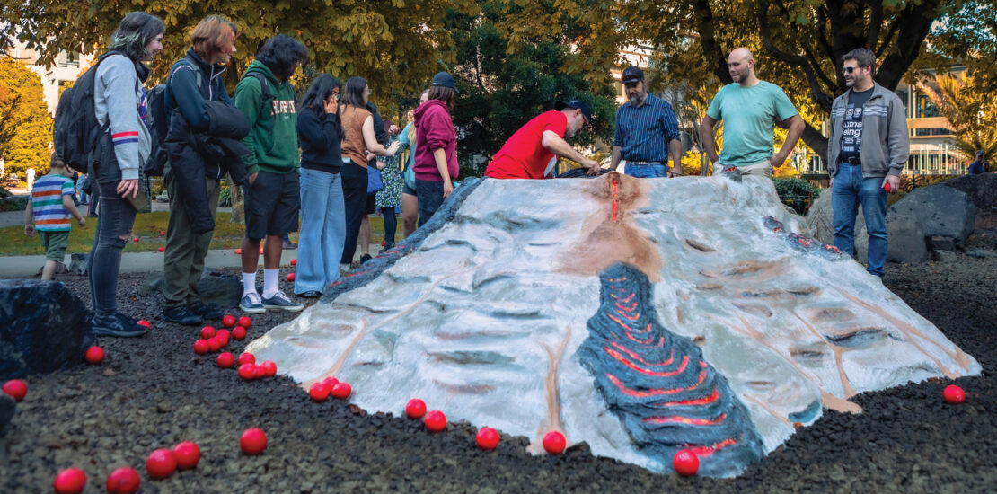 Students release red balls down the slopes of a model volcano as a learning exercise outdoors in New Zealand
