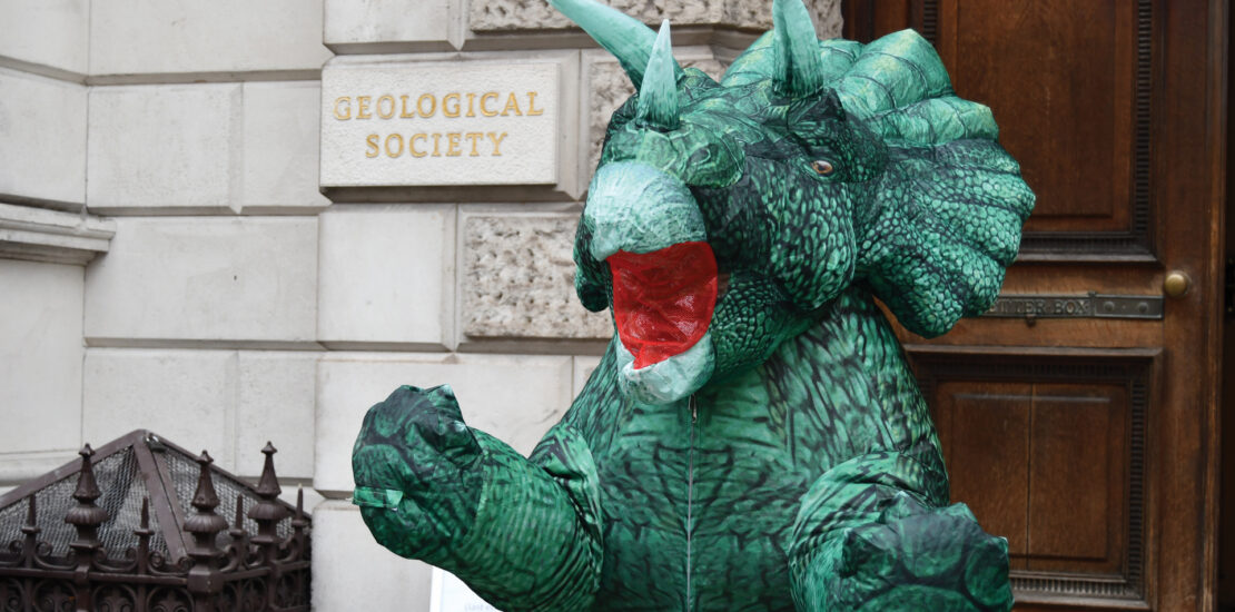 A person is dressed up inside a dinosaur costume.