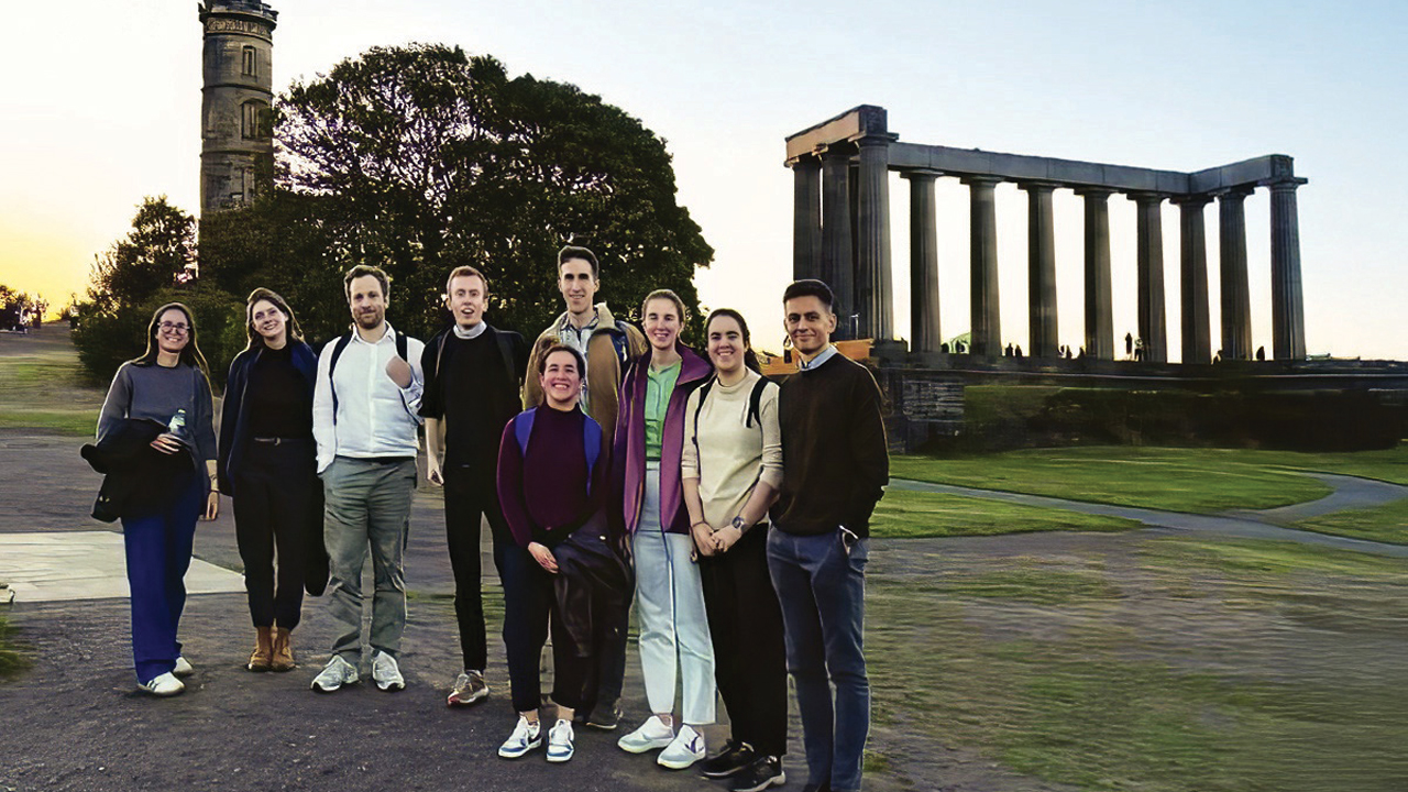 A group of young geologists pose for a photo in front of an old monument.