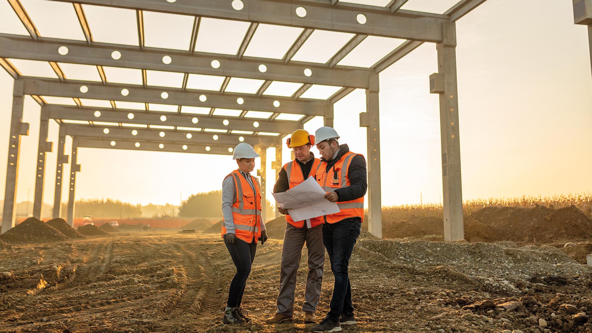 Male and female architects discussing over blueprint at construction site