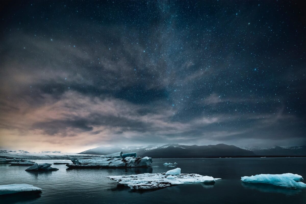 Icy landscape with rock, sea and icebergs, under a starry sky