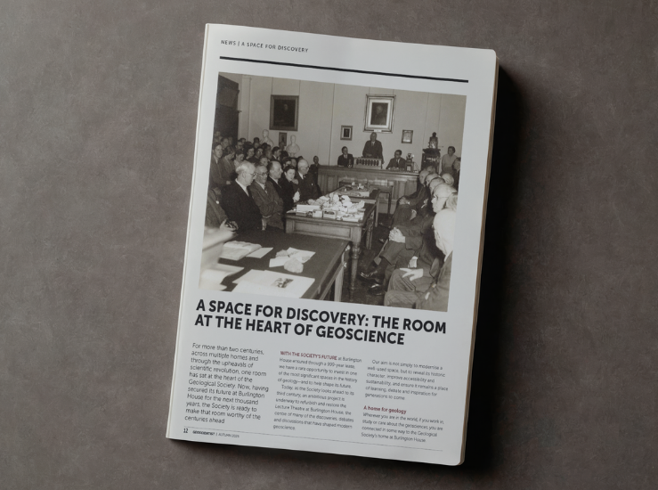 A magazine lying on a desk showing a black and white photo of a lecture theatre